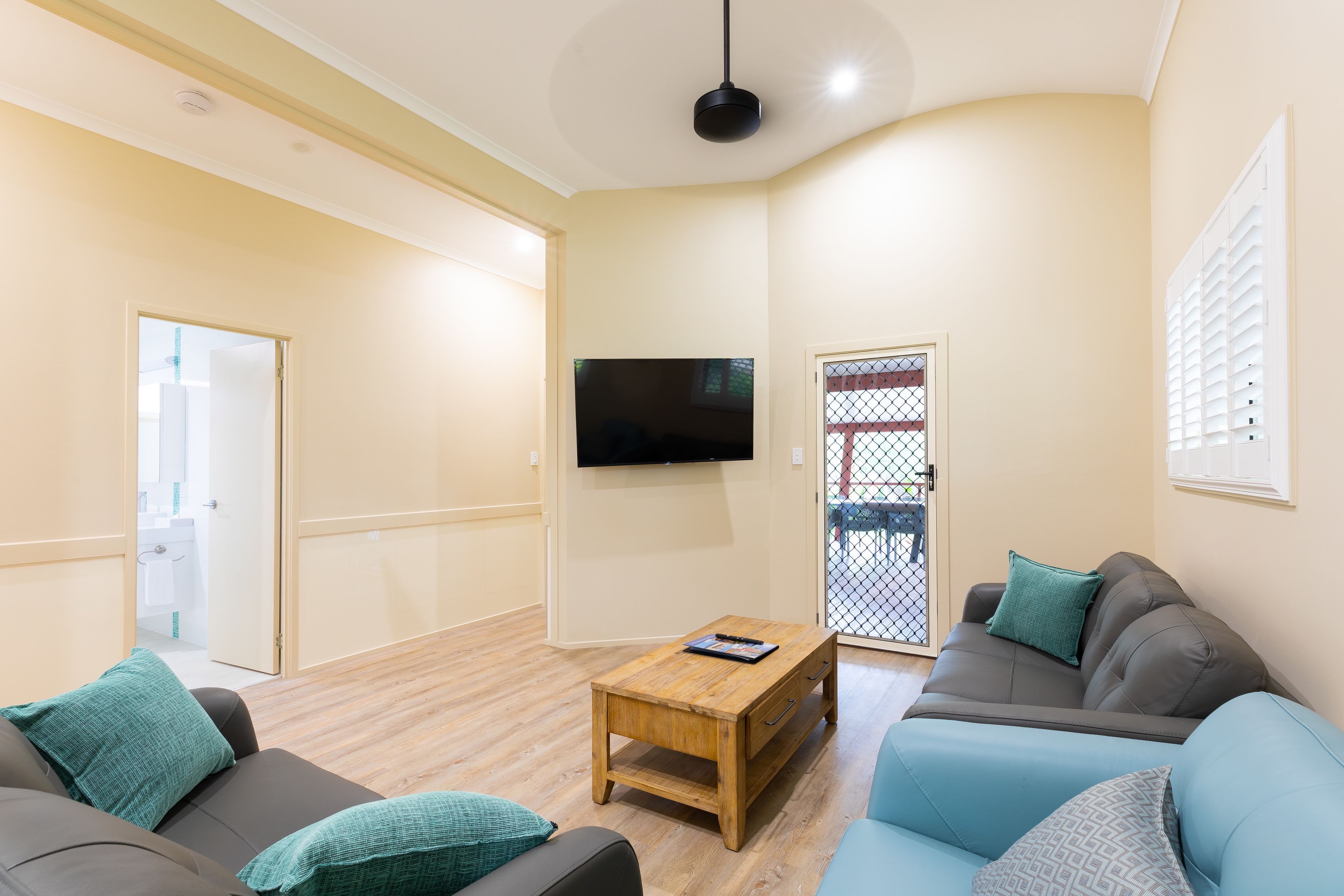 A living room with a sofa, a coffee table, and a TV mounted on the wall.