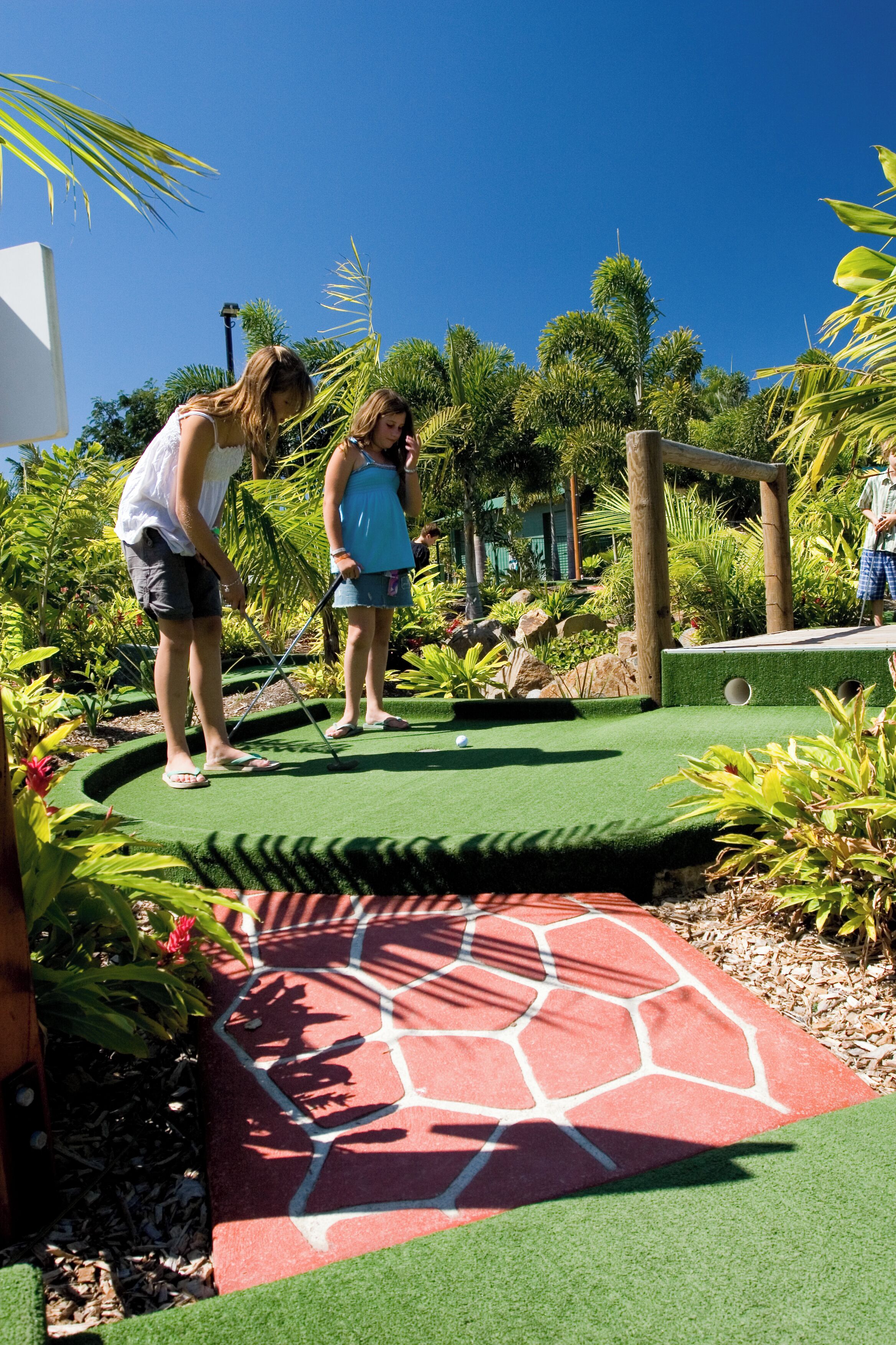A miniature golf course with a green putting surface and a red patterned area.