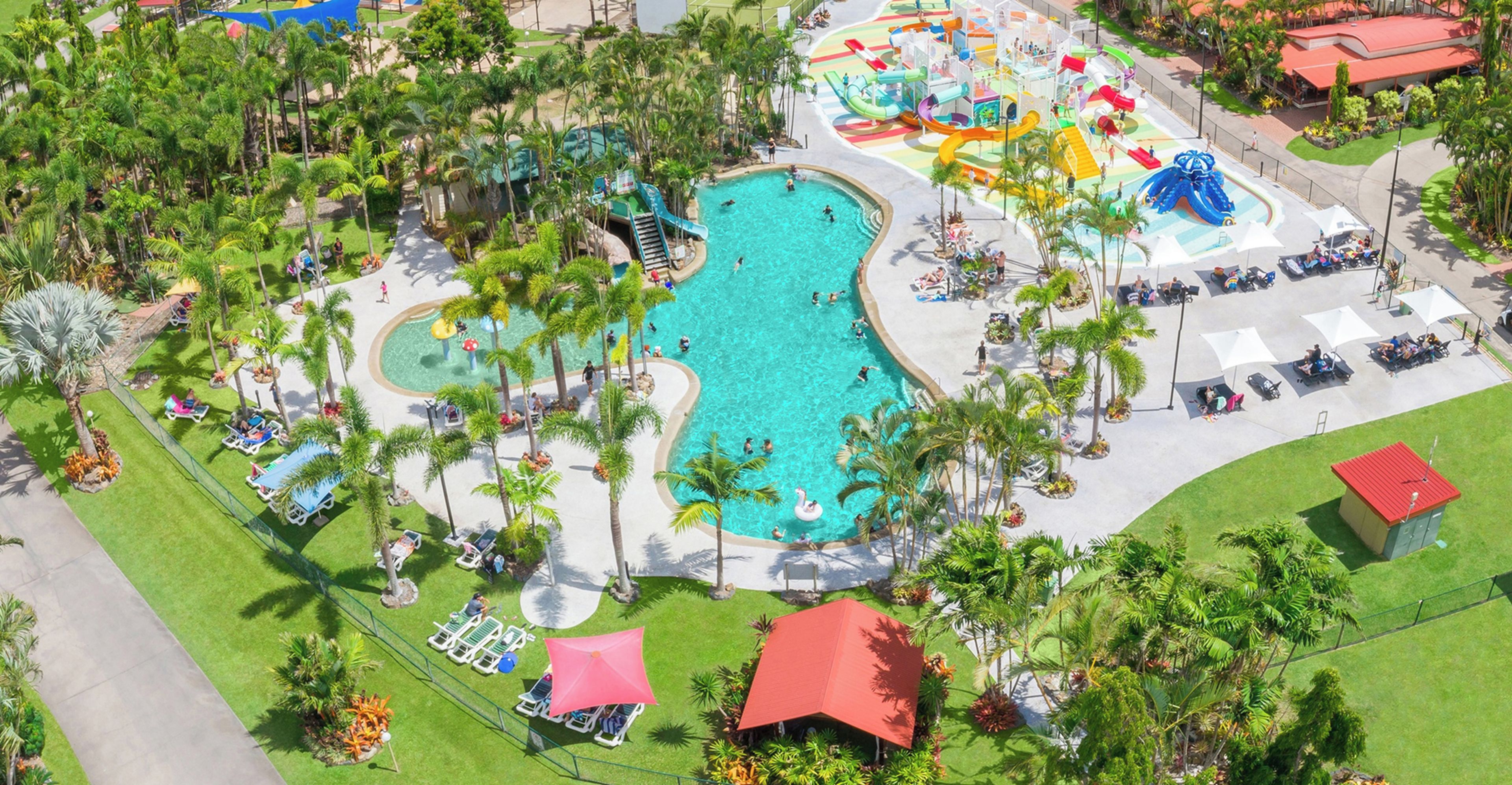 Vista aérea de un complejo turístico con una piscina central, varias toboganes acuáticos y tumbonas.