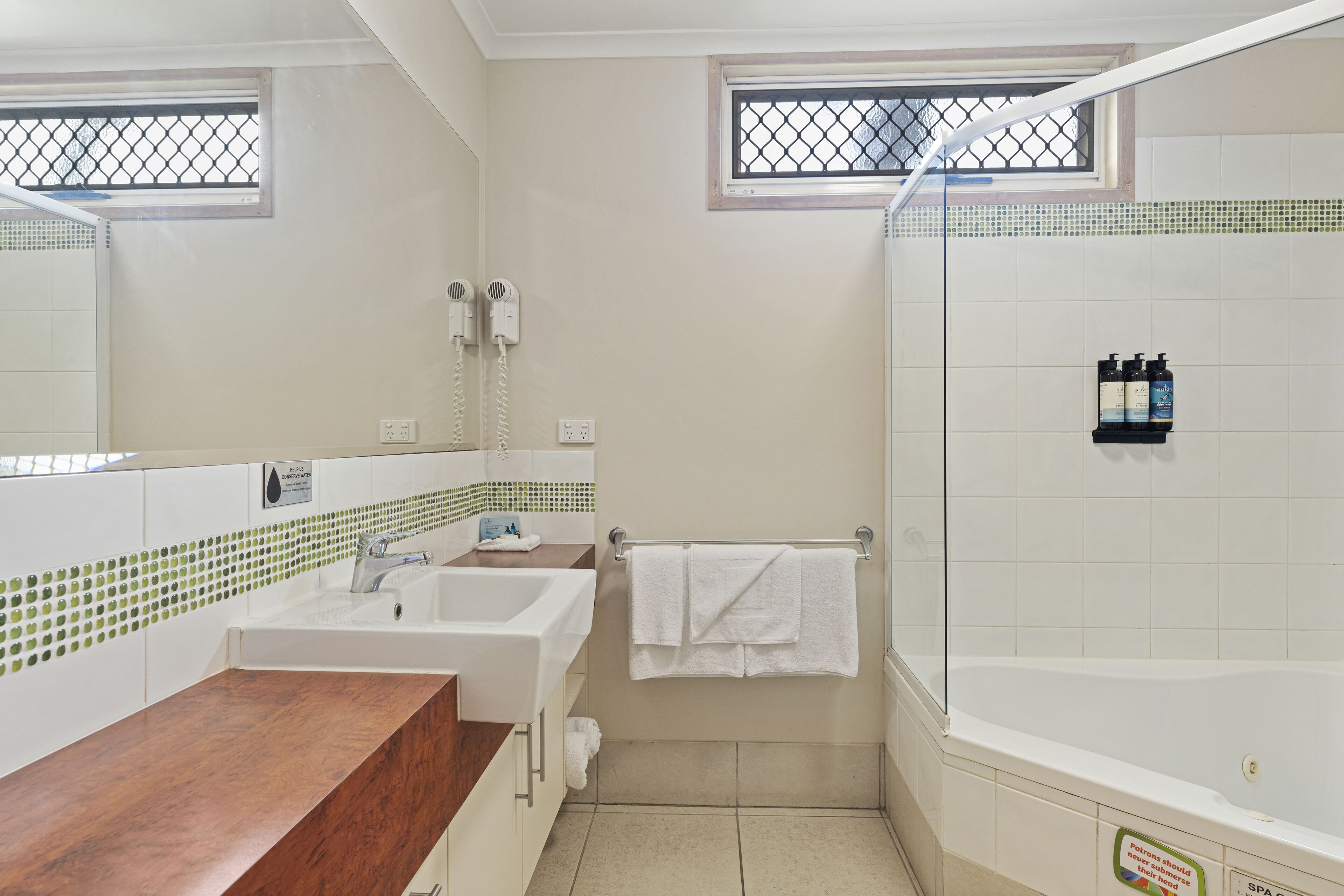 A bathroom with a sink, mirror, and a shower area.