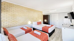 A hotel room with two beds, a brick wall, a wardrobe, a desk with a computer, and a microwave. - Tropical Gate Motor Inn (Allenstown)