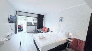 Habitación de hotel moderna con una cama grande, un escritorio, una silla, un televisor y vistas al exterior.