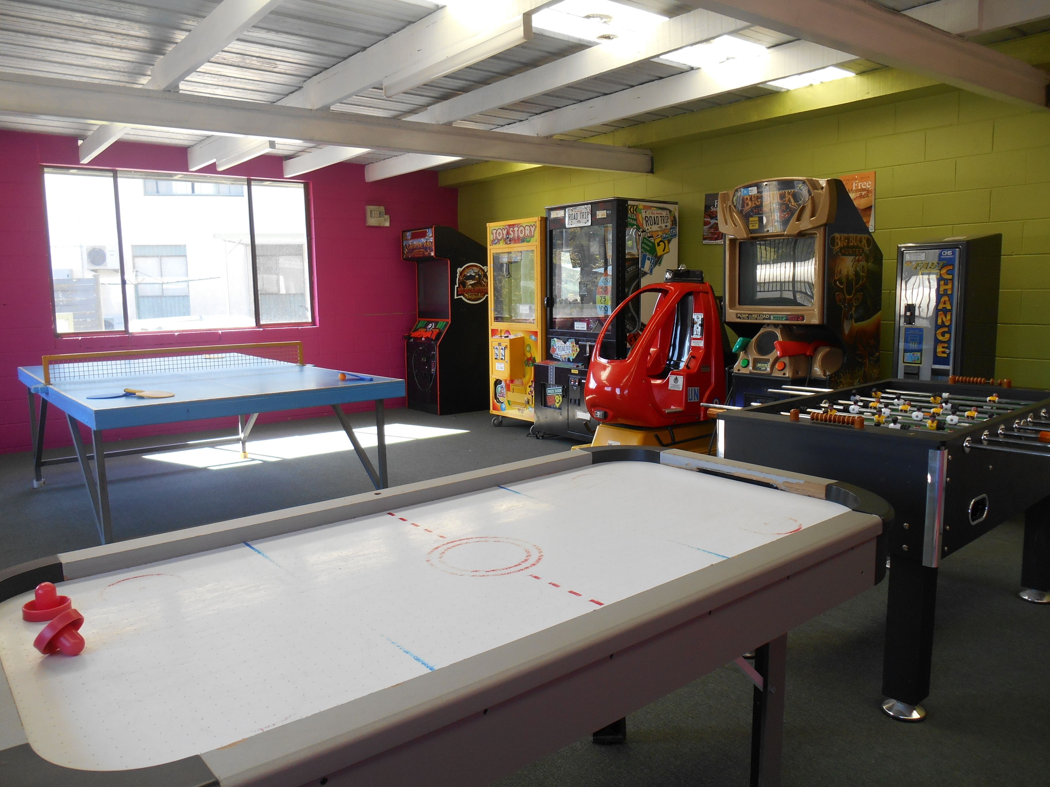 Een recreatieruimte met een tafelvoetbaltafel, pingpongtafel en diverse spelautomaten.