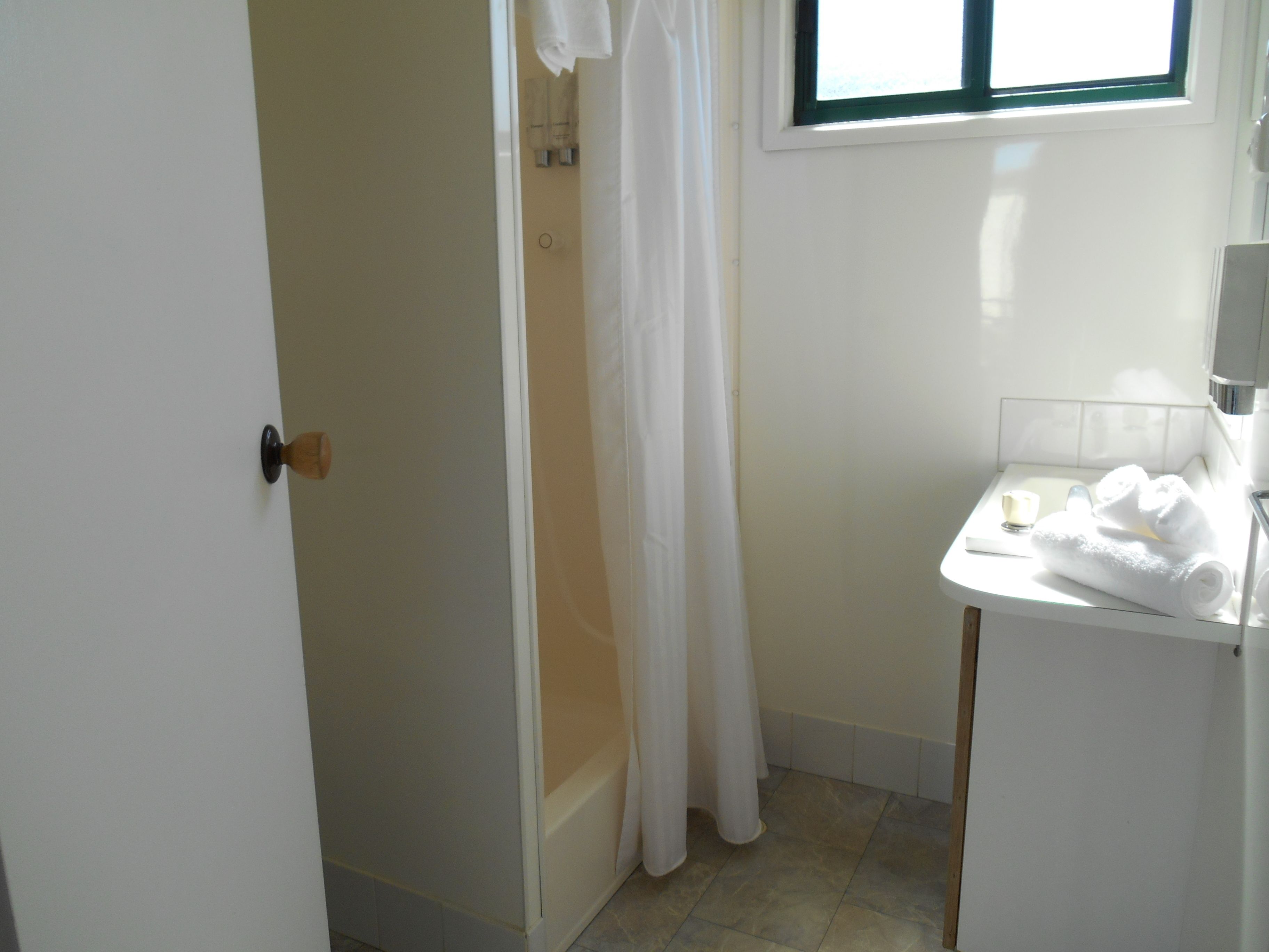 Un baño con ducha, un lavabo con espejo y un perchero para toallas.