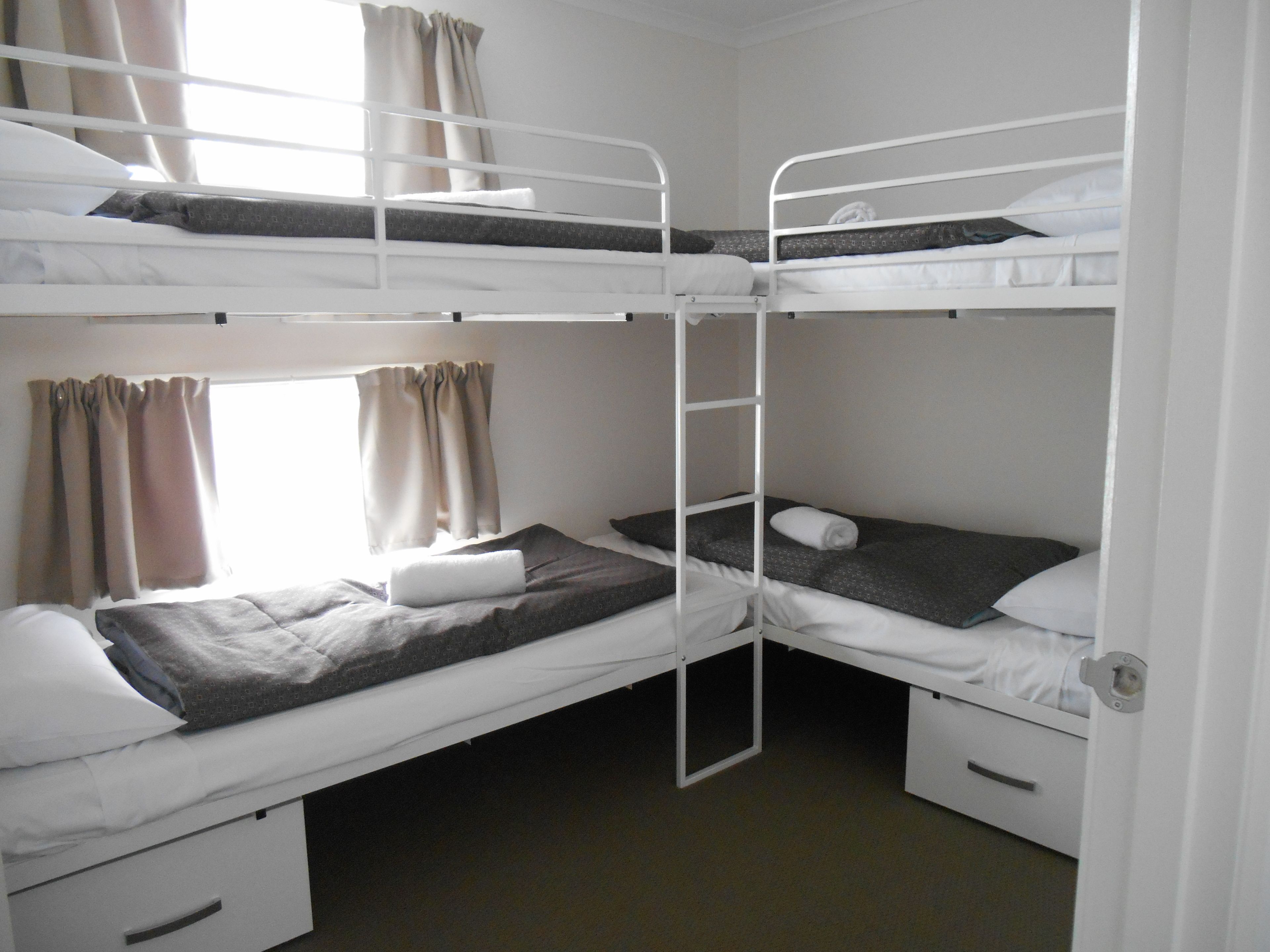 Une chambre avec un lit superposé, comprenant deux lits, une fenêtre avec des rideaux et une porte.