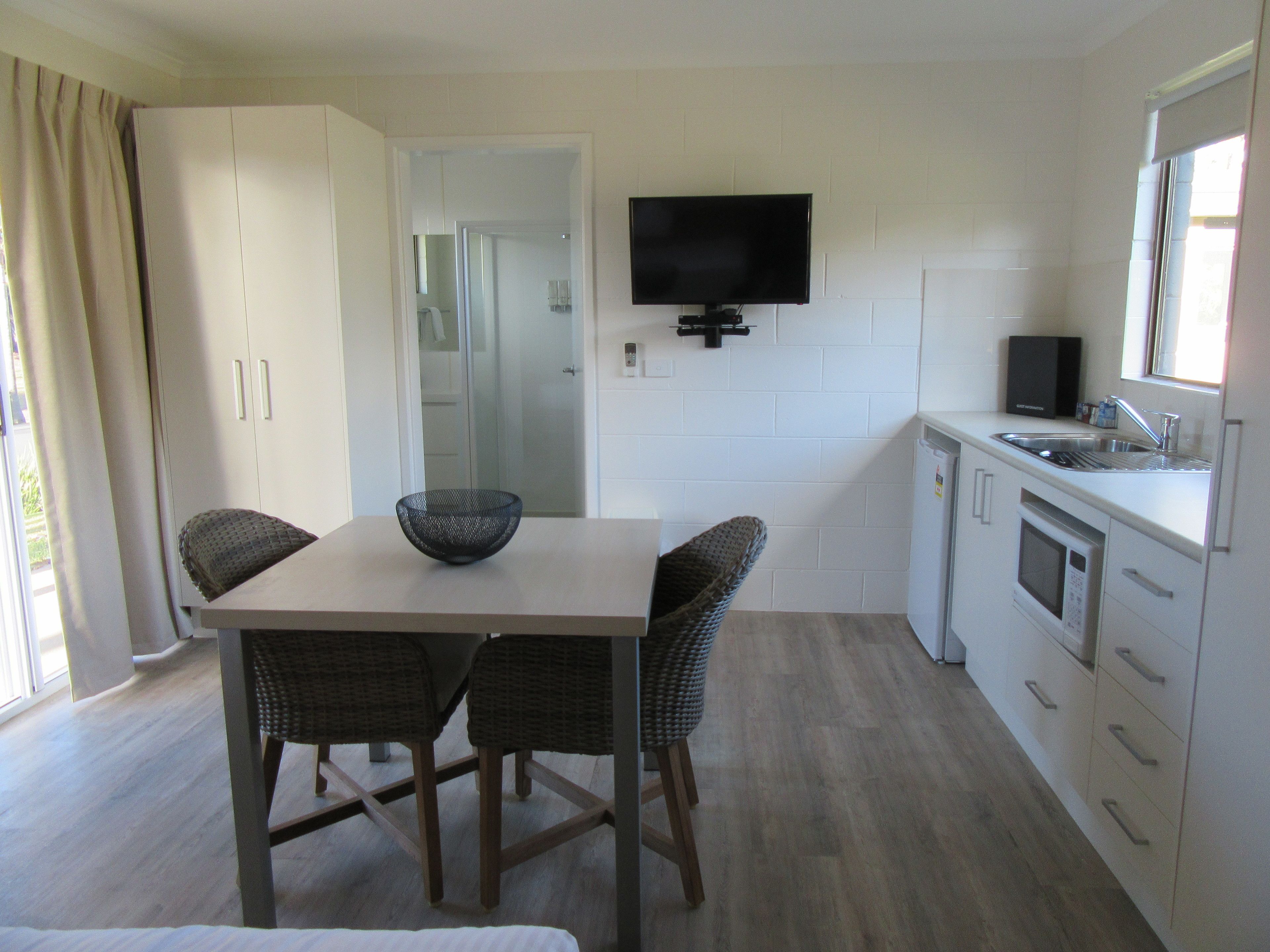 Una cocina moderna con una mesa de comedor, sillas, un televisor y un lavamanos.
