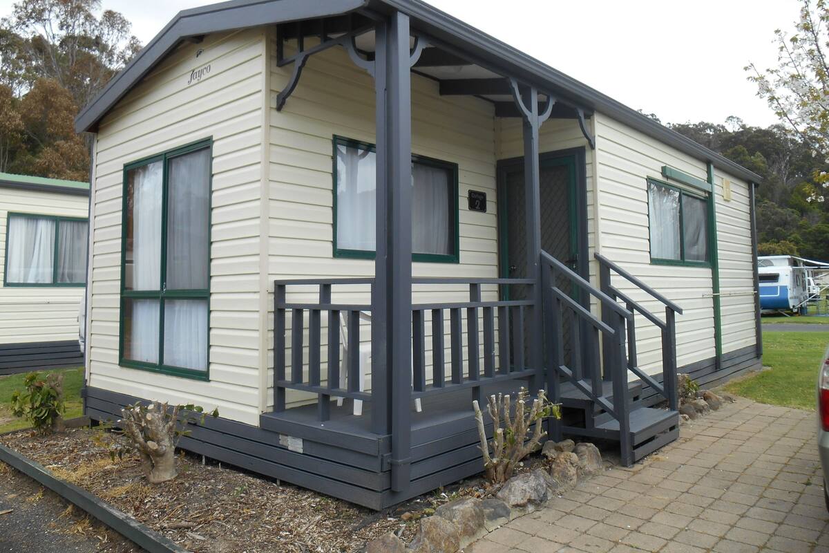 A single-story mobile home with a porch and a staircase leading to the entrance.