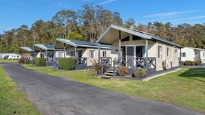 A row of mobile homes with solar panels, a paved driveway, and a grassy area with trees in the background. - Tasman Holiday Parks – Merimbula (Merimbula)
