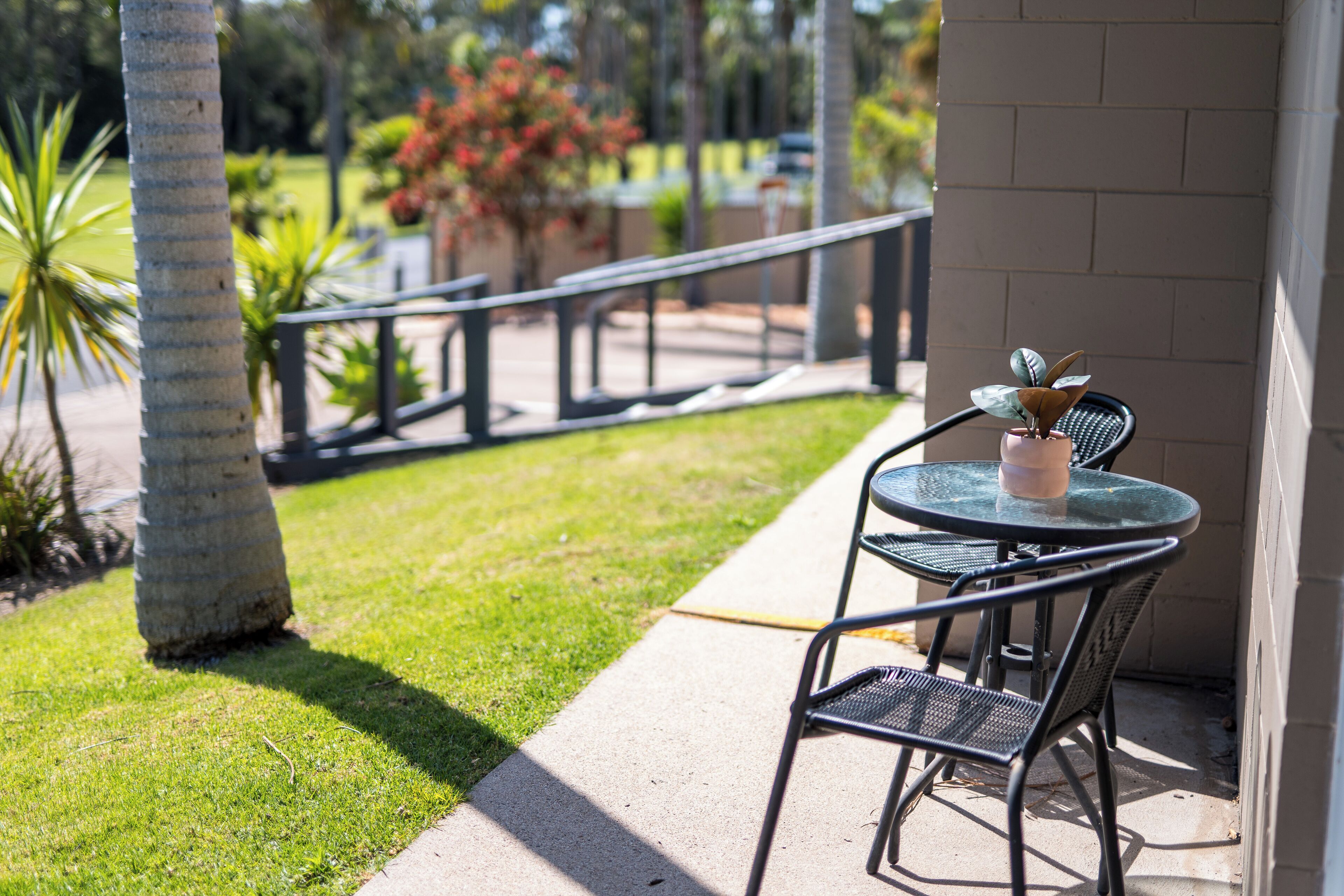 A patio with a table and chairs, a railing, and a potted plant.
