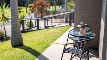 A patio with a table and chairs, a railing, and a potted plant.