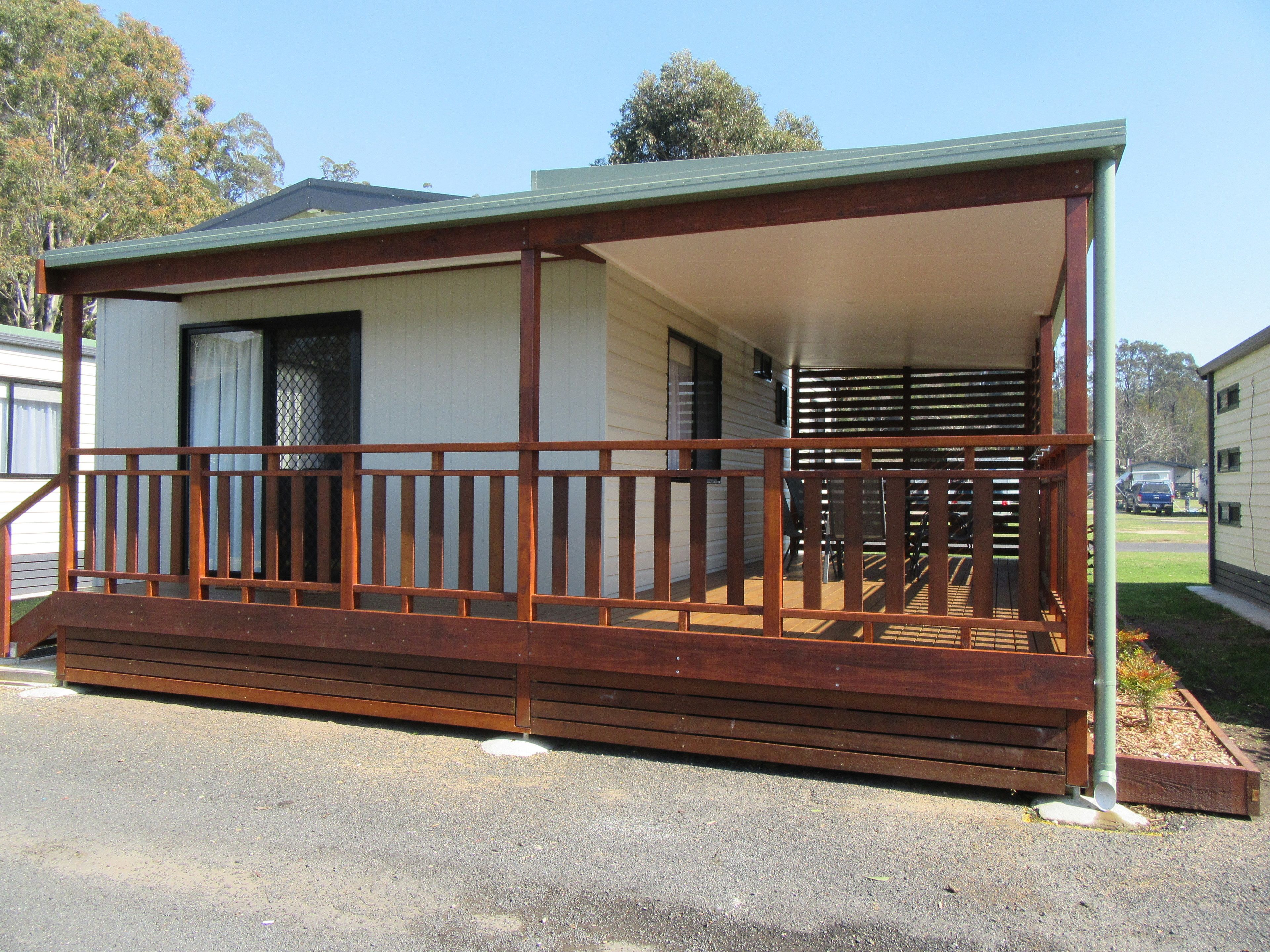 A single-story mobile home with a covered porch and a fenced deck area.