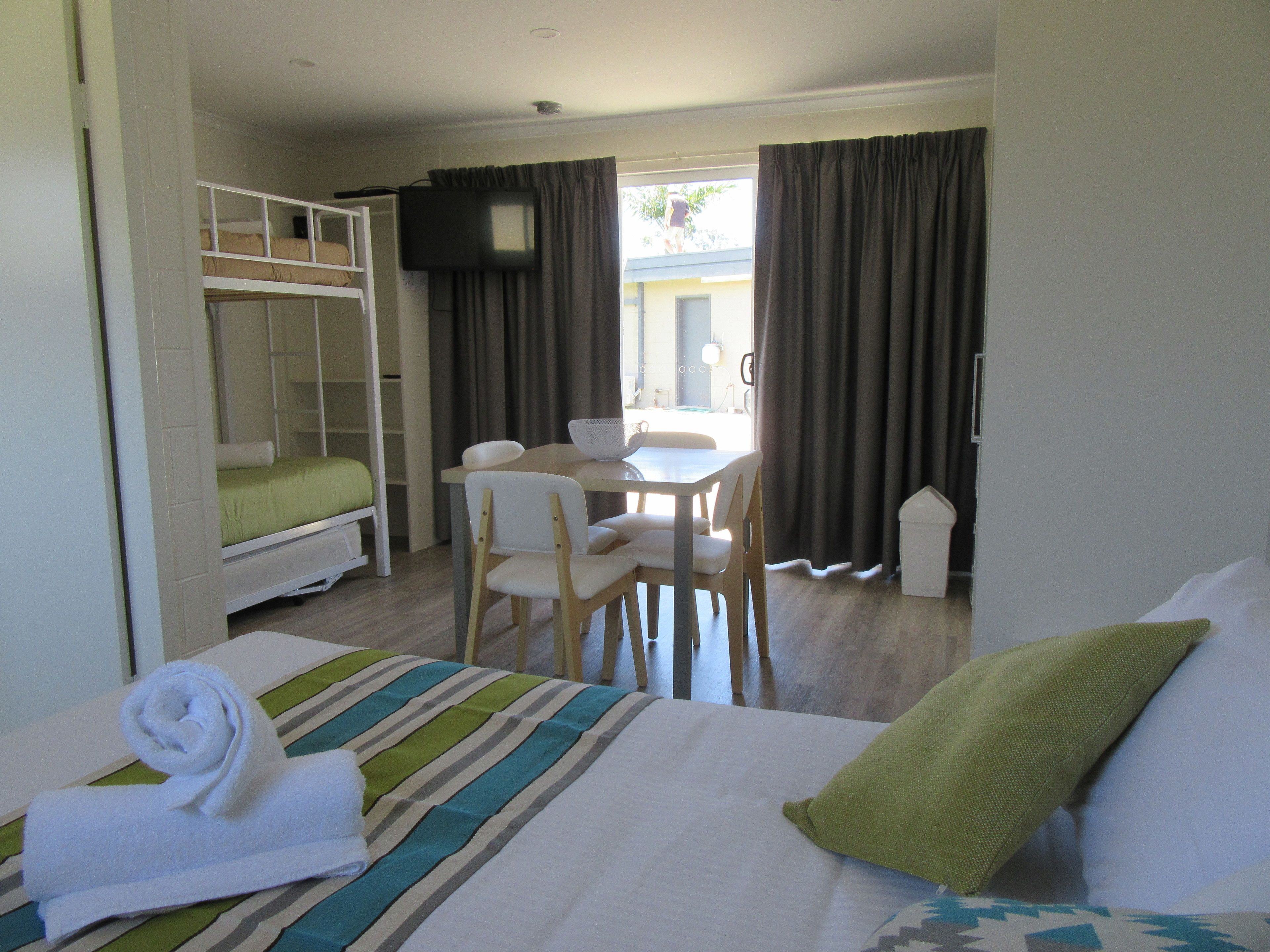 A hotel room with a bed, a desk, a chair, a television, and a window with curtains.
