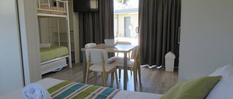 A hotel room with a bed, a desk, a chair, a television, and a window with curtains.