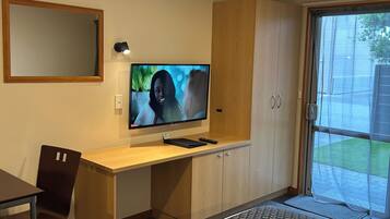 A modern room with a desk, chair, TV, and sliding glass door to a patio.