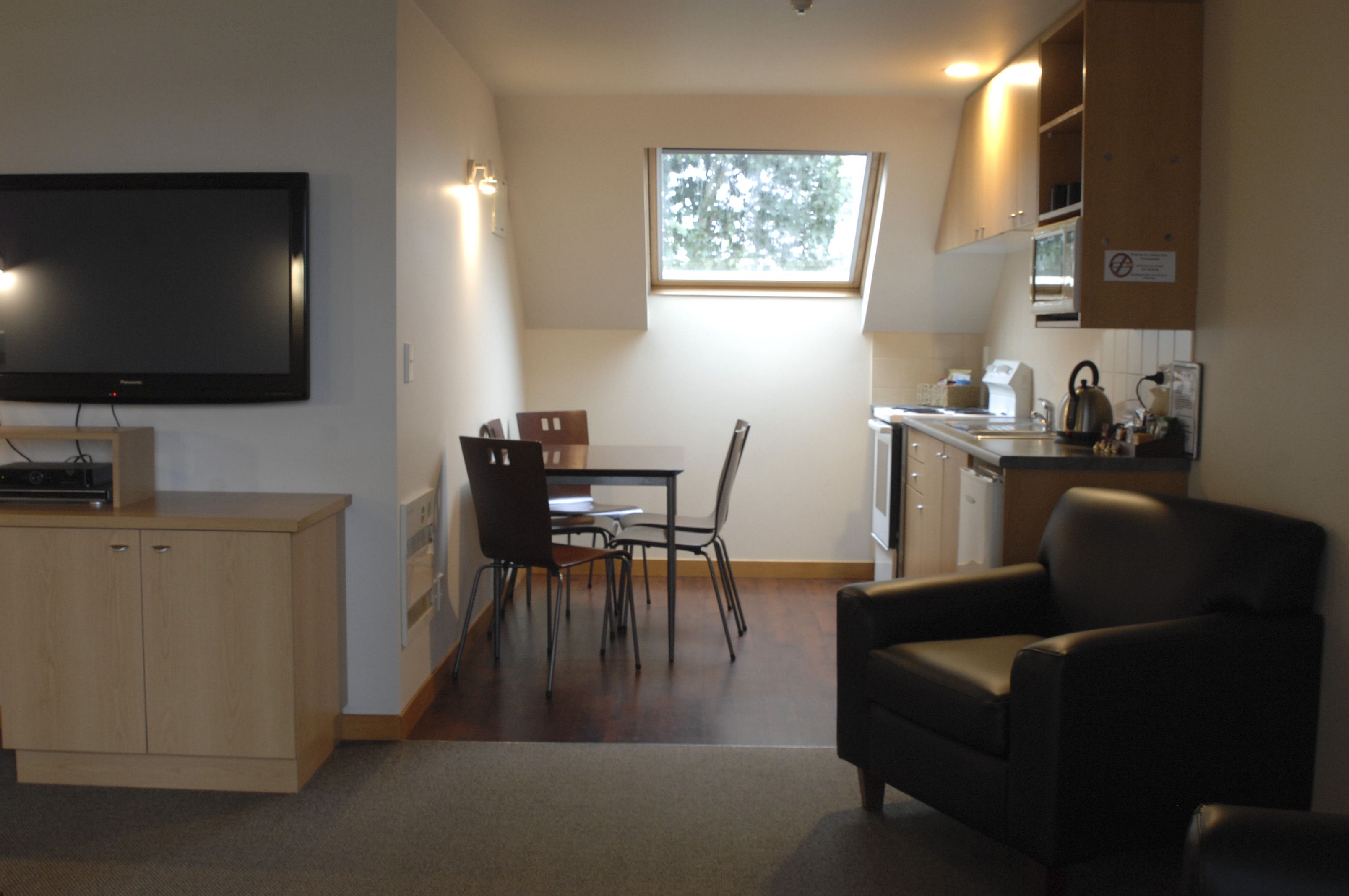 A compact living space with a TV, dining area, and kitchenette.