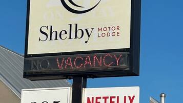 Schild für das Shelby Motor Lodge mit einem Pferdelogo, das keine freien Zimmer anzeigt. Es wirbt außerdem mit kostenlosem WLAN und Netflix.