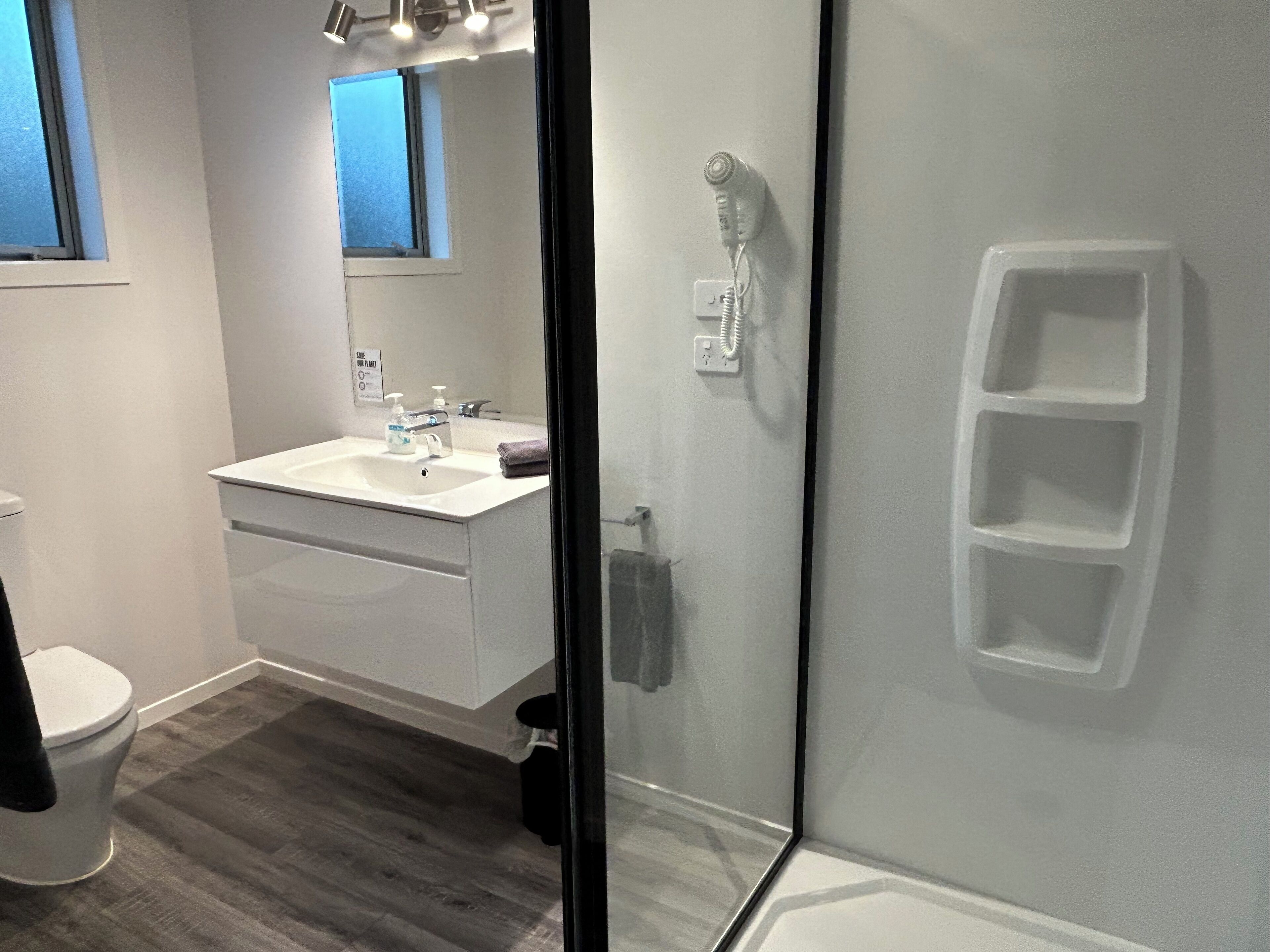 A modern bathroom with a white sink, mirror, and shower.