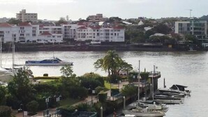 Una propiedad frente al mar con un puerto deportivo, edificios de techos rojos y vegetación.
