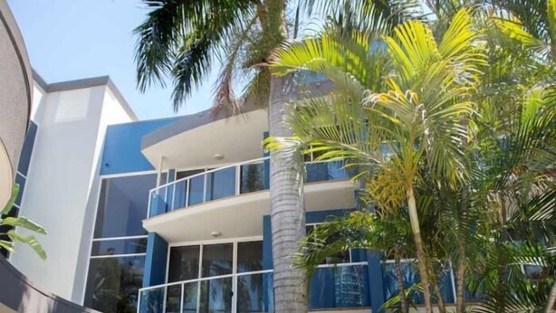 Un edificio moderno con fachada azul y blanca, ventanas amplias y un balcón.