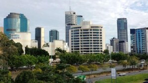 Un paisaje urbano con modernos rascacielos, una combinación de edificios residenciales y comerciales, y una calle con vehículos.