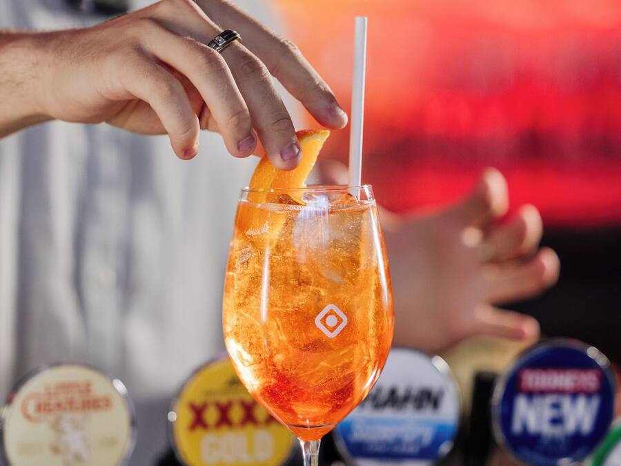 A bartender preparing a cocktail with a straw in a glass.