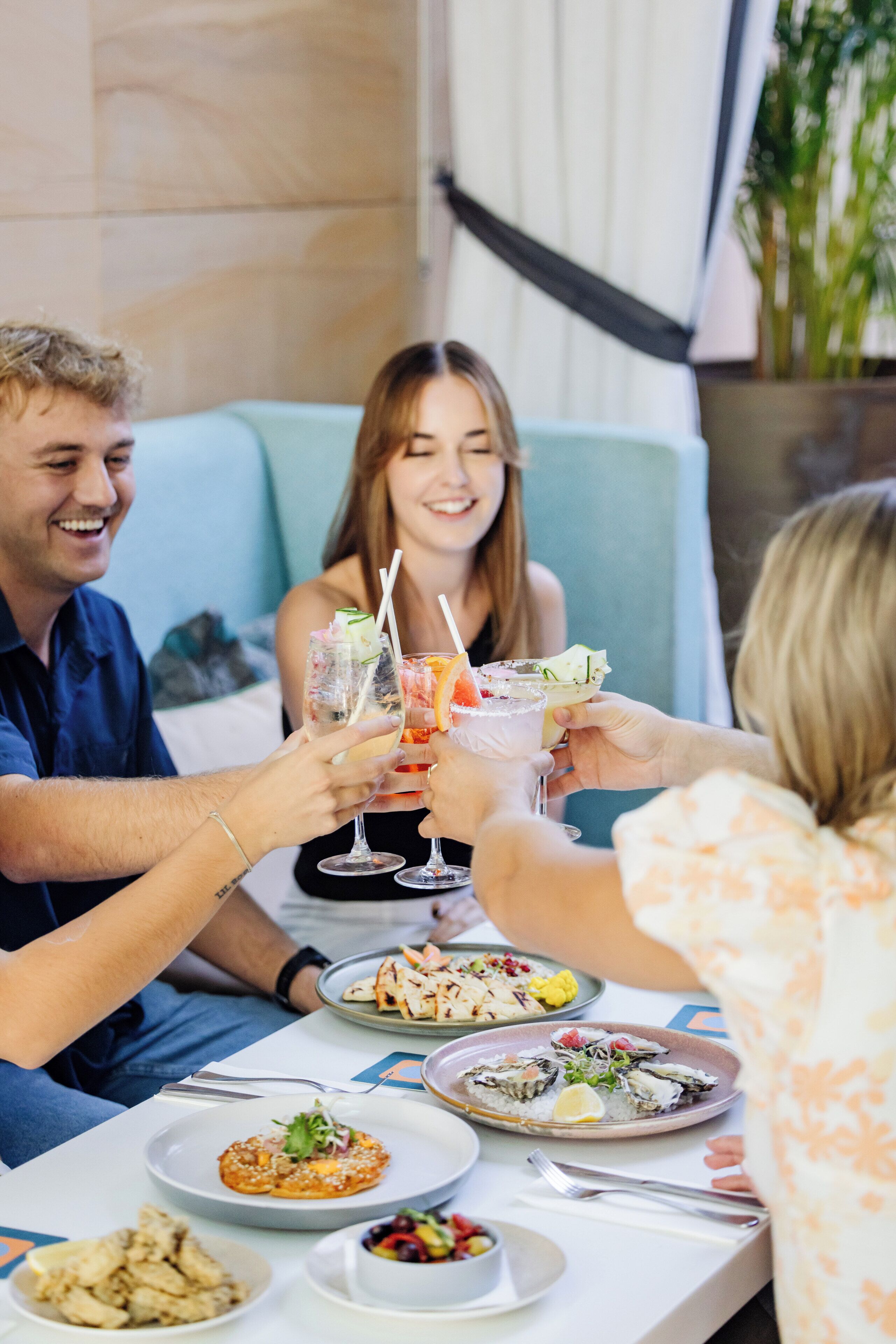A group of people toasting with drinks at a table with various dishes.