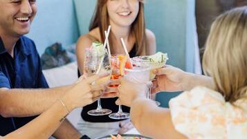 A group of people toasting with drinks at a table with various dishes.