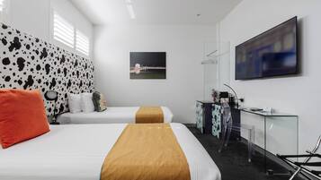 Een hotelkamer met twee bedden, een bureau, een stoel, een televisie en een schilderij aan de muur.