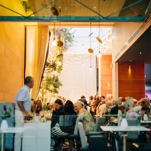Een restaurantinterieur met tafels, stoelen en hanglampen.