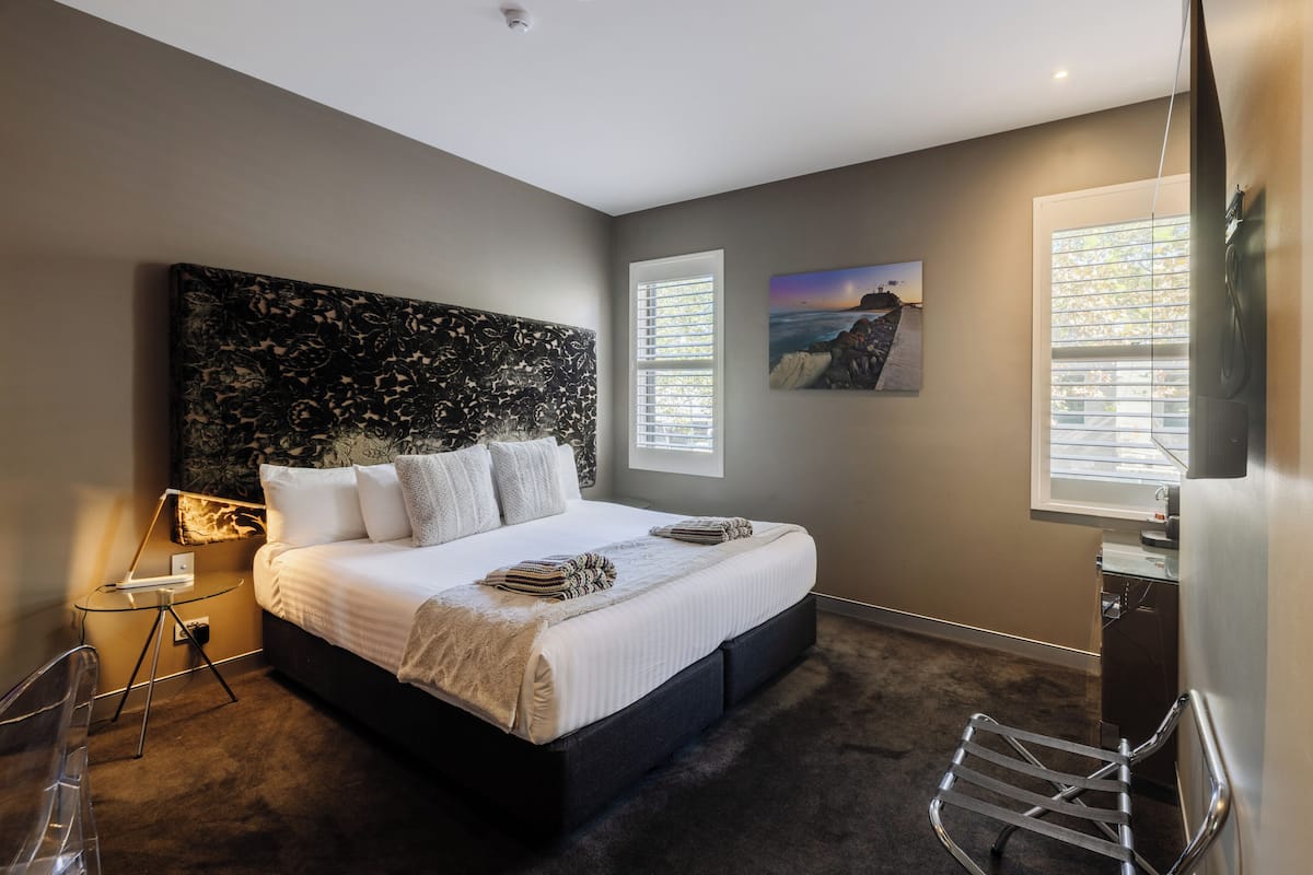 A modern bedroom with a large bed, a desk, and a chair.