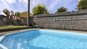 A swimming pool with a wooden fence, a lounge chair, and a palm tree. - Cunningham Shore Motel (Lakes Entrance)