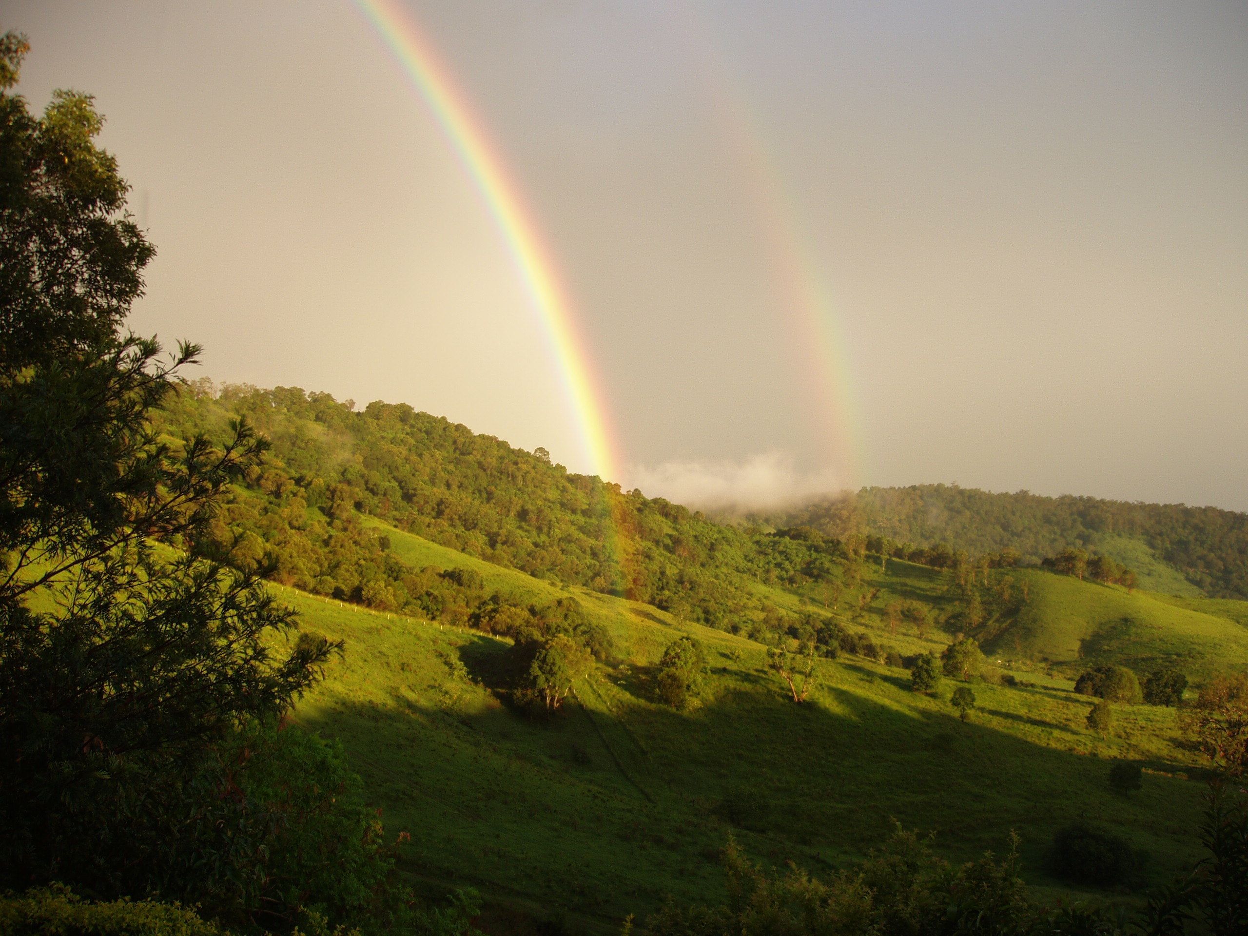 A landscape with a rainbow over a green valley.