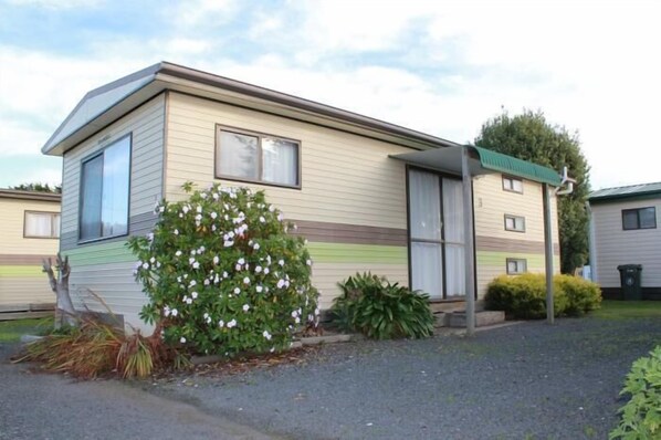 A single-story mobile home with a flat roof, a small porch, and a front window. - Abel Tasman Caravan Park (East Devonport)