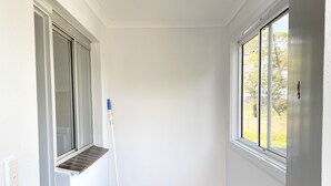 A hallway with a window, a door, and a mop leaning against the wall.