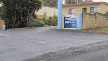 Segnaletica per Limestone Coast Tourist Park, con un edificio in mattoni e un pilastro blu.