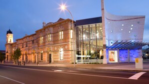 A historic building with a clock tower and a modern glass extension.
