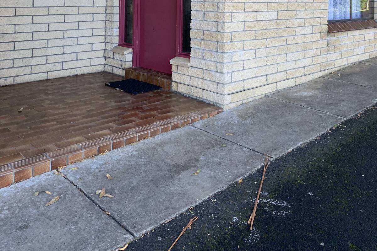 Een tweelaags bakstenen gebouw met een rode deur en een raam op de begane grond.