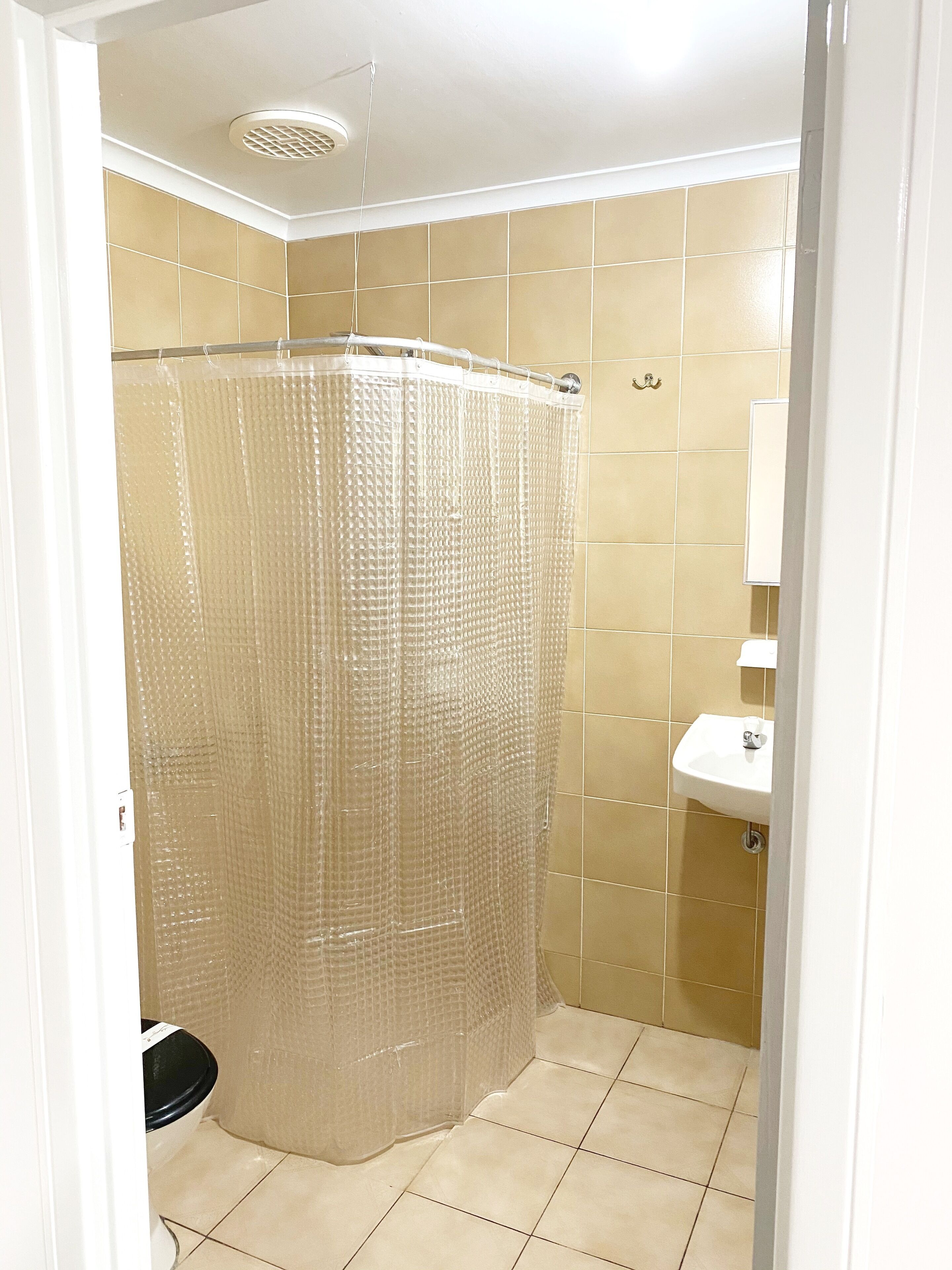 A bathroom with a shower curtain, a sink, and a toilet.