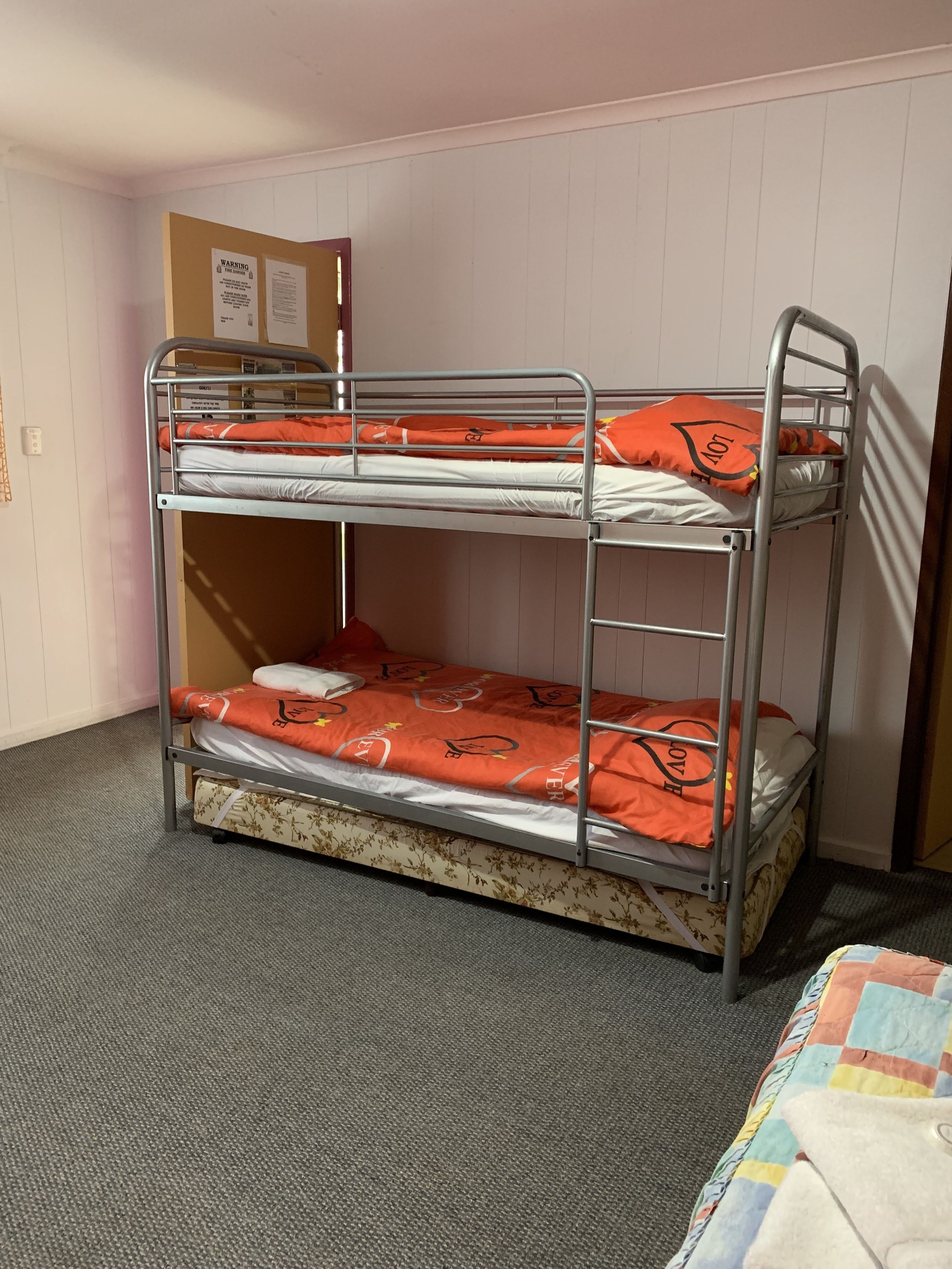 Una litera con ropa de cama naranja y una cama inferior con estampado floral.