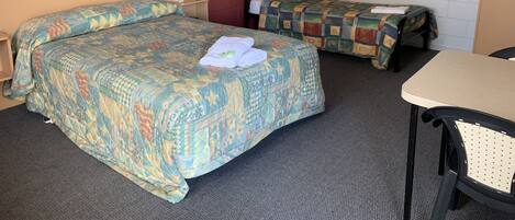 A hotel room with two beds, a desk, a chair, and a picture on the wall.