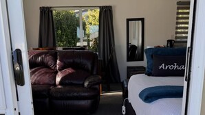 A bedroom with a bed, a leather sofa, a rug, and a view of the outdoors.