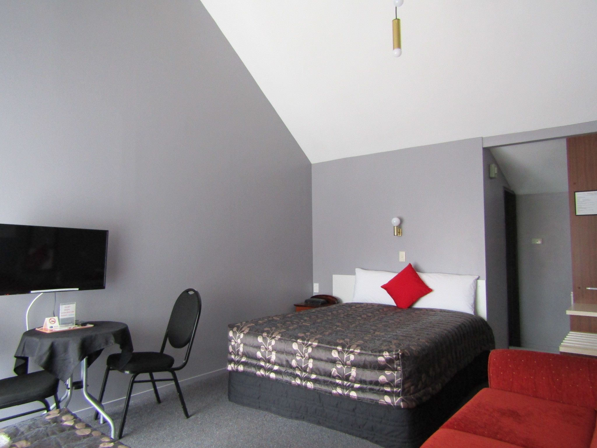 Ein Hotelzimmer mit Bett, Fernseher, Schreibtisch und Stuhl.