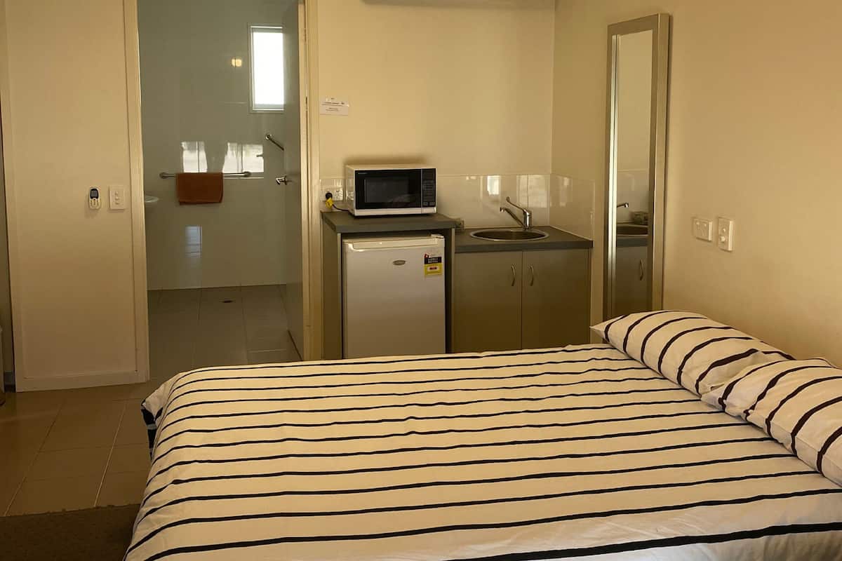 Ein Hotelzimmer mit Bett, einer kleinen Küchenzeile, einem Deckenventilator und einer Klimaanlage.