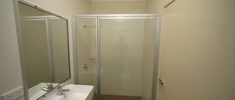 A bathroom with a glass-enclosed shower, a white sink, and a mirror.