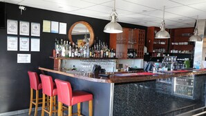 A bar area with a counter, stools, and shelves with bottles. - Black Rock Inn (Blackwater)