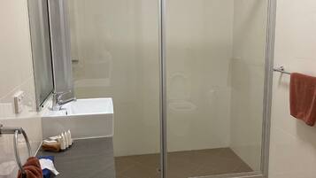 A modern bathroom with a glass-enclosed shower, a sink with toiletries, and a towel rack.
