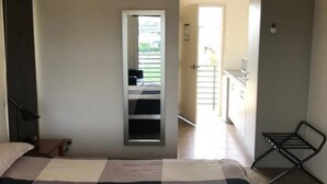 A bedroom with a large bed, a small desk, a chair, and a view of a balcony. - Black Rock Inn (Blackwater)