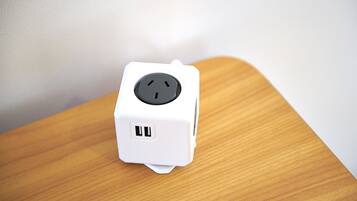 A white power strip with two USB ports and a three-prong plug on a wooden surface.