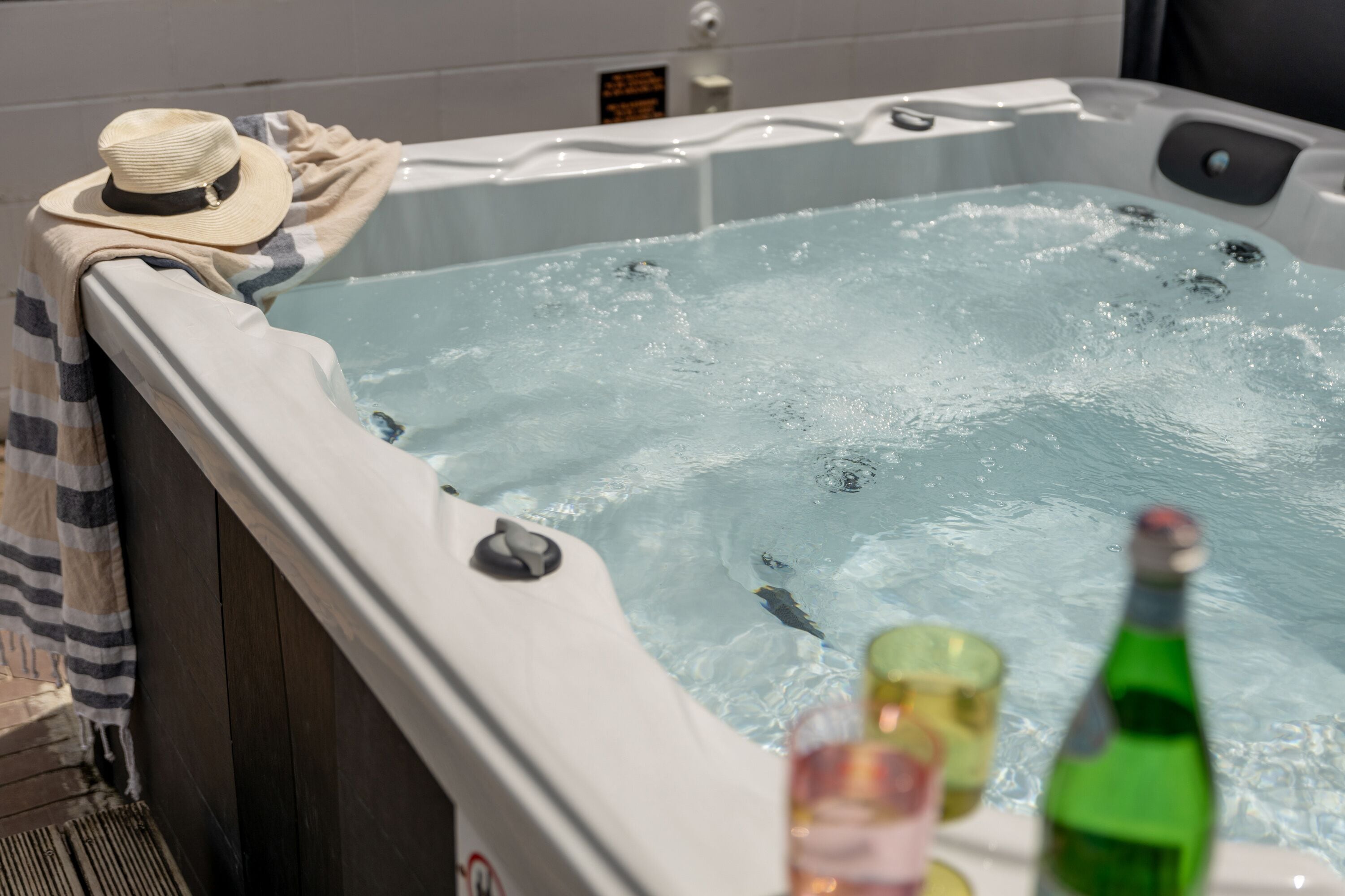 A hot tub with a hat and a bottle on the edge.