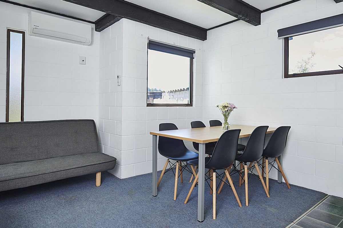 A room with a sofa, a table with chairs, and a window with a view.